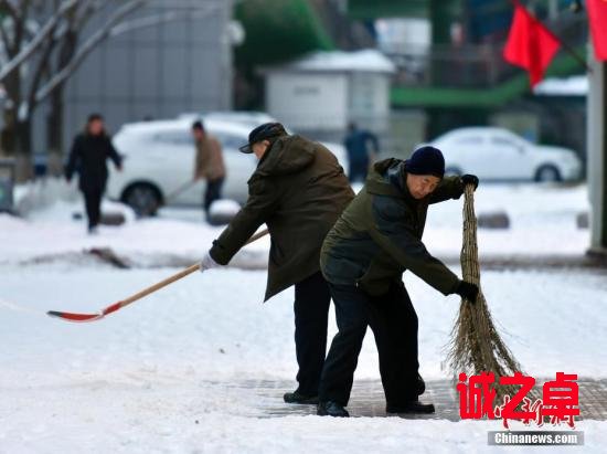 农历狗年正月初一,民众在乌鲁木齐街头清理人行道上的积雪。中新社记者 刘新 摄