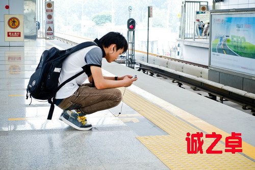 资料图片:2012年7月18日,在北京地铁立水桥站,一名年轻人在候车期间查看手机。新华社发